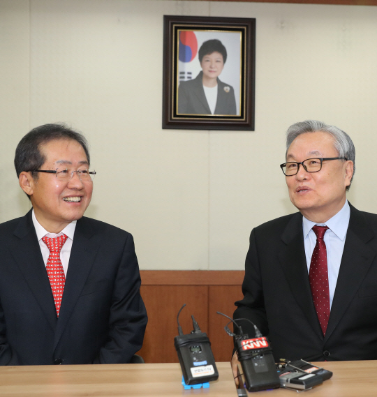 인명진(오른쪽) 자유한국당 비상대책위원장이 9일 오전 서울 여의도 당사에서 홍준표 경남지사를 만나 환담하고 있다. 두 사람 뒤로 탄핵심판 선고를 하루 남긴 박근혜 대통령의 사진이 걸려있다./연합뉴스