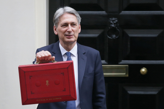 필립 해먼드 영국 재무장관이 8일(현지시간) 런던 관청가인 다우닝가에서 예산안 공표를 위해 의회로 출발하기에 앞서 재무장관의 상징이 된 예산안이 담긴 붉은 박스를 들어보이고 있다. /런던=신화연합뉴스