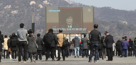 10일 오전 광화문 광장에서 시민들이 헌법재판소의 박근혜 대통령 탄핵심판 선고 방송을 보고 있다.