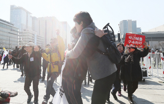 탄핵 인용 발표 직후 서울 광화문 광장에서 시민들이 박근혜 대통령 파면 결정에 포옹하고 있다.