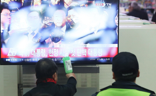 10일 오전 경기도 수원시 대합실에서 한 시민이 박근혜 대통령 탄핵 인용 결정에 술병을 들고 TV를 때리며 항의하고 있다.