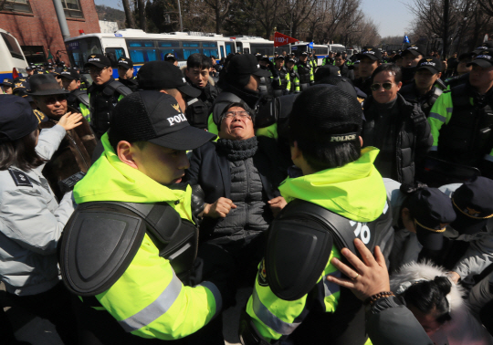 10일 오후 서울 종로구 청운동사무소 앞에서 경찰이 탄핵에 반대하며 도로에 앉아있는 한 시민을 인도로 옮기고 있다.