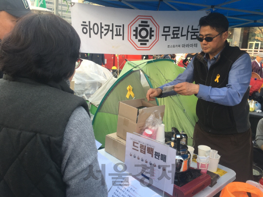 일 광화문 광장에서 열린 촛불집회의 한 참석자가 무료로 따뜻한 커피를 나눠주고 있다. /변수연기자