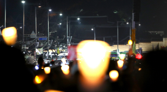 헌법재판소의 탄핵인용으로 박근혜 전 대통령이 파면된 10일 서울 광화문 광장에서 열린 촛불 집회에 참가한 시민들이 든 촛불과 불이 꺼진 청와대가 대비되고 있다. /연합뉴스