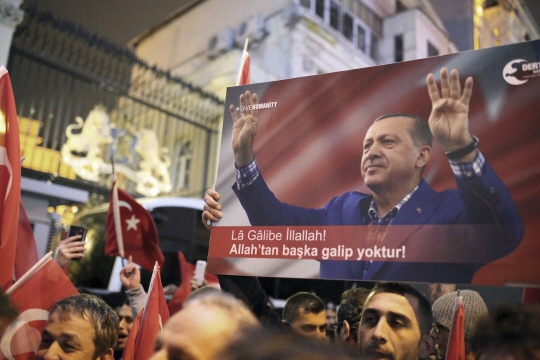 12일(현지시간) 터키 이스탄불 시내에서 열린 레제프 타이이프 터키 대통령 지지 집회에서 사람들이 터키 국기와 대통령 사진을 들고 있다. /이스탄불=AP연합뉴스