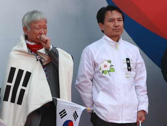 지난 11일 오후 서울 덕수궁 대한문 일대에서 열린 탄핵무효국민총궐기운동본부 주최 태극기 집회에서 전날 집회 사망자를 추모하는 검정 리본을 단 자유한국당 김진태 의원과 태극기를 두른 박근혜 전 대통령 측 대리인 서석구 변호사(왼쪽)가 나란히 단상에 서 있다. / 연합뉴스