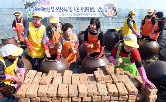 17일 서초구청 주최로 서초구 대원농장에서 열린 사랑 담아 된장 간장 만들어요 행사에 참석한 자원봉사자들이 항아리에 메주를 넣고 있다. 이 행사는 주민과 기업 봉사자 60여명이 참여, 오는 10월께 저속득 독거 어르신 및 소년소녀 가장 등 300여세대에 전달 예정이다./이호재기자