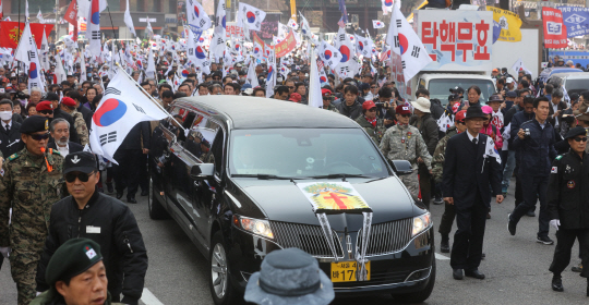 18일 오후 ‘대통령 탄핵무효 국민저항 총궐기 운동본부’ 회원들이 대한문 앞에서 헌재 인근 시위에서 사망한 김모씨 등을 위한 추모행사를 한 후 운구를 하고 있다. /연합뉴스