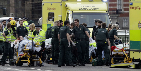22일(현지시간) 차량 테러가 발생한 영국 런던 웨스트민스터 다리에서 구급대원들과 경찰들이 부상자들을 구급차로 이송하고 있다. 이 사건으로 용의자를 포함한 5명이 사망하고 40명이 부상했다. 영국 경찰은 용의자가 이슬람 극단주의에 경도된 자생적 테러리스트인 ‘외로운 늑대’일 가능성에 무게를 두고 수사를 벌이고 있다.  /런던=AP연합뉴스
