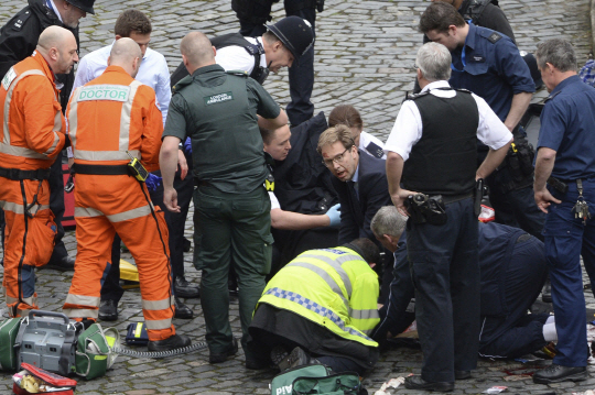 토비어스 엘우드(가운데) 영국 외무차관이 22일(현지시간) 런던 웨스트민스터궁 입구에서 테러범이 휘두른 칼에 찔린 경찰관에게 심폐소생술을 실시하고 있다. /런던=AP연합뉴스