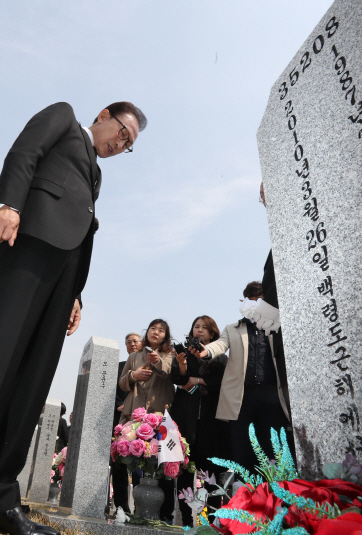 이명박 전 대통령이 23일 대전 유성구 국립대전현충원 ‘천안함 용사 46용사 묘역’에서 참배하고서 묘비를 살펴보고 있다./연합뉴스