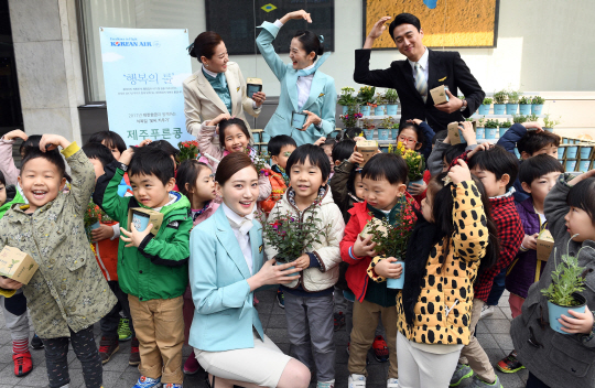 식목일을 앞두고 30일 오전 서울 중구 대한항공 서소문 사옥에서 열린 꽃씨나눔 행사에서 승무원들이 어린이들에게 제주푸른콩 화분을 나눠주며 기념촬영하고 있다./이호재기자.