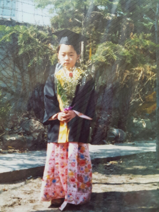 유치원 졸업식에서 고운 한복을 차려입고 꽃다발을 든 채 기념사진을 찍고 있는 일곱살 때의 서경미 대표.