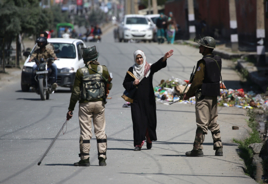 한 무슬림 여성이 인도 카슈미르주 주도 스리나가르 시내에서 통과 허가를 얻기 위해 군병을 향해 손을 들고 있다. /스리나가르=AFP연합뉴스