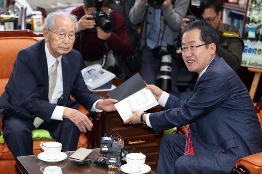 홍준표(오른쪽) 자유한국당 대선 후보가 12일 오후 서울 용산구 전쟁기념관에서 백선엽 장군을 예방하고 국가안보에 대한 조언을 구한 뒤 책을 선물받고 있다./연합뉴스