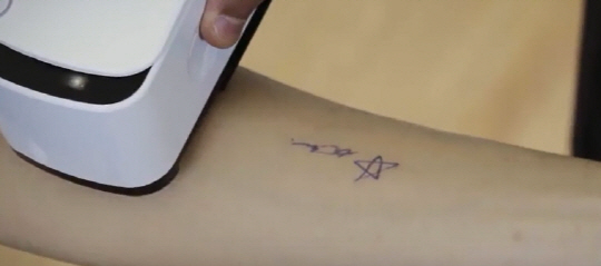 스킨 프린터 ‘프링커’로 팔에 문신을 새기는 모습./사진=유튜브 캡쳐