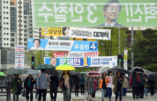 전국에 봄비가 촉촉이 내리고 있는 17일 시민들이 각 당 대선후보들의 현수막이 설치된 서대문의 한 건널목을 건너고 있다. 제19대 대선 공식 선거운동이 시작된 이날 각 당 대선후보들은 벽보와 현수막 등을 전국 곳곳에 걸고 유권자들의 표심을 공략하고 나섰다.  /이호재기자