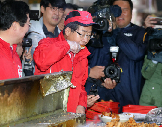 자유한국당 홍준표 대선후보가 17일 대전 중앙시장을 찾아 상인이 건네준 닭고기구이를 먹고 있다. /연합뉴스