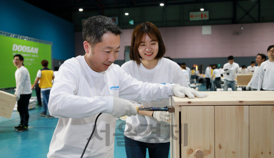 박정원 두산그룹 회장이 19일 ‘두산인 봉사의 날(Doosan Day of Community Service)’을 맞아 대치동 서울무역전시컨벤션센터에서 임직원들과 함께 지역사회 가정에 전달할 가구를 만들고 있다./사진제공=두산