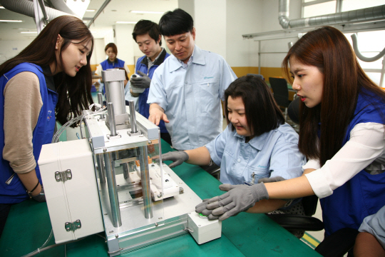 경기도 수원에 위치한 장애인작업장 ‘행복을 만드는집’ 직원들이 삼성전자 제조기술그룹 봉사팀이 설계한 간이자동 기기를 통해 핸드 청소기 롤러 바퀴를 쉽게 조립하고 있다./사진제공=삼성전자