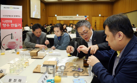 지난 19일 서울 충무로 CJ인재원에서 열린 ‘올리브영 시각장애인과 함께하는 나만의 향수 만들기’ 행사에서 올리브영 임직원 봉사단 ‘쉐어 위드 올리브(Share With Olive)’가 시각장애인 30명과 함께 향수를 만들고 있다./사진제공=올리브영