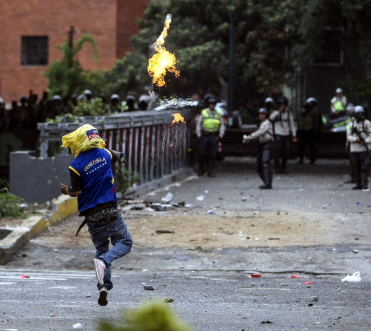 베네수엘라 정부에 반대하는 시위자가 20일(현지시간) 수도 카라카스에서 경찰을 향해 화염병을 던지고 있다.    /카라카스=EPA연합뉴스