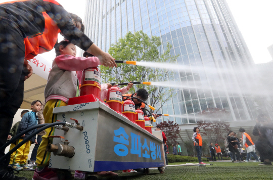 28일 ‘세계 안전의 날’을 맞아 서울 송파구 신천동 롯데월드타워 아레나광장에서 열린 ‘송파소방서 안전문화 체험행사’에서 어린이들이 직접 소화기를 사용해 화재 진압을 체험하고 있다.           /연합뉴스