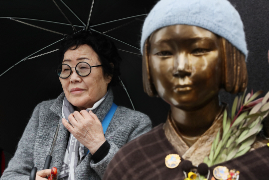 위안부 피해자인 이용수 할머니가 소녀상 뒤에서 우산을 쓴 채 앉아있다. /연합뉴스