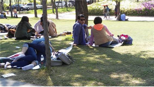 지난달 23일 서울 영등포구 선유도공원 잔디 위에 20대 남여가 서로 부둥켜 안고 누워 있는 모습을 한 시민이 바라보고 있다. /신다은기자