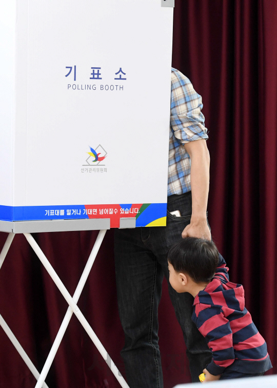 19대 대통령선거 사전투표 둘째 날인 5일 서울 광진구 구의제2동 주민센터에 마련된 사전투표소에서 한 시민이 아이의 손을 잡고 투표하고 있다.  /권욱기자