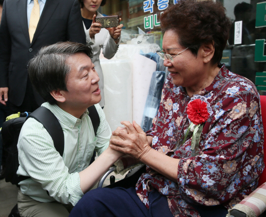 안철수(왼쪽) 국민의당 후보가 8일 충남 천안시 동남구 중앙시장에서 한 어르신에게 카네이션을 달아주며 인사를 나누고 있다./연합뉴스