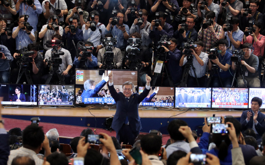 더불어민주당 문재인 후보가 9일 오후 서울 여의도 국회의원회관 개표상황실에 들어서 두 손을 번쩍 들고 승리를 확신하는 표정을 짓고 있다.