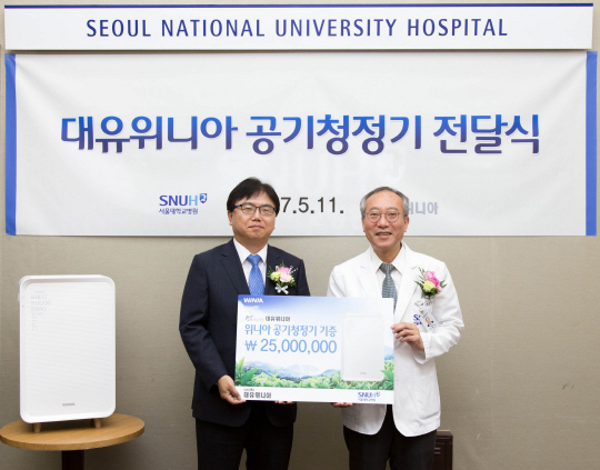 박성관(왼쪽) 대유위니아 대표가 서창석 서울대병원장에게 위니아 공기청정기를 전달하고 있다./사진제공=대유위니아