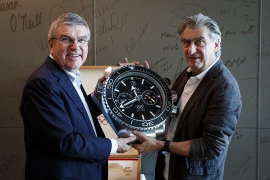 토마스 바흐(왼쪽) IOC 위원장과 닉 하이에크 스와치그룹 회장이 16일 파트너십 계약연장에 사인한 뒤 오메가 시계를 들어 보이고 있다. /사진제공=오메가