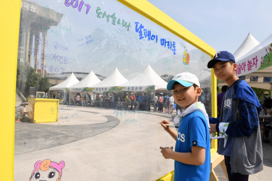 달팽이 마라톤에 참가한 아이들이 투명판넬에 도시숲에 대한 바람을 적고 있다.