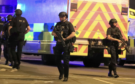 무장 경찰들이 22일(현지시간) 폭발사고가 일어난 영국 북부 맨체스터 경기장을 조사하고 있다. 경찰은 테러 가능성이 있다고 보고 정확한 상황을 수사 중이다. /멘체스터=AP연합뉴스