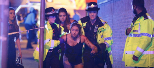 22일(현지시간) 영국 경찰이 맨체스터 아레나에서 발생한 자살폭탄 테러로 부상한 한 여성을 부축해 아레나를 빠져나오도록 돕고 있다.  /트위터 캡처