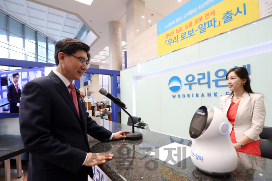 24일 서울 회현동 우리은행 본점에서 이광구(왼쪽) 우리은행장이 ‘우리 로보-알파’를 탑재한 실물 로봇을 통해 자산관리 상담을 받고 있다./사진제공=우리은행