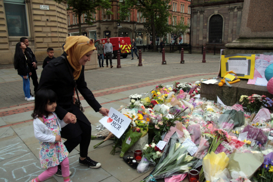 한 무슬림 여성이 멘체스터 테러 희생자들을 추모하는 꽃다발이 놓인 광장에서 조문하고 있다./UPI연합뉴스
