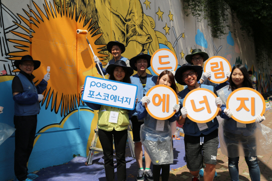 인천 서구 석남3동에서 26일 진행된 벽화 그리기 봉사활동에서 포스코에너지 관계자들이 행사 피켓을 들어 보이고 있다./사진제공=포스코에너지