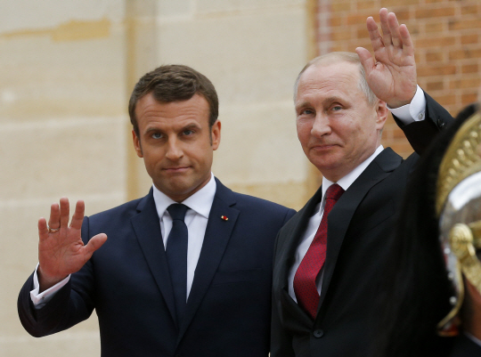 에마뉘엘 마크롱(왼쪽) 프랑스 대통령과 블라디미르 푸틴 러시아 대통령이 29일(현지시간) 파리 외곽 베르사유 궁에서 만나 기자들을 향해 함께 손을 흔들고 있다. /파리=AP연합뉴스