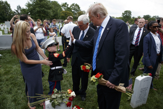 도널드 트럼프(오른쪽) 미국 대통령이 29일(현지시간) 미국 버지니아주 알링턴 국립묘지에서 열린 ‘메모리얼데이’ 기념식에 참석해 희생 장병의 아들인 여덟 살짜리 크리스천 제이컵스(가운데)와 하이파이브를 하고 있다. 트럼프 대통령은 기념식 연설에서 “희생 장병은 신이 우리에게 보낸 천사였다”며 “그들은 신이 부르기 전까지 여기 잠시 머물렀지만 그들이 남긴 업적은 영원할 것”이라고 애도했다.        /알링턴=AP연합뉴스