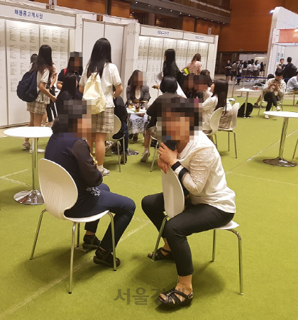 지난 24일 서울 삼성동 코엑스에서 열린 ‘중견기업 채용박람회’를 찾은 취업준비생 어머니들이 행사장 테이블 의자에 앉아 잠시 쉬면서 자녀들과 통화하고 있다./백주연 기자
