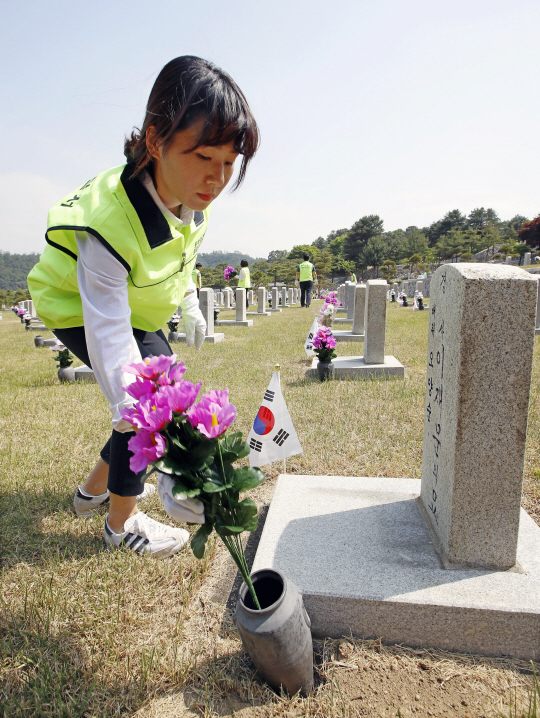 호국보훈의 달을 앞둔 31일 서울 동작구 국립서울현충원에서 동작경찰서 직원들이 묘비에 무궁화 조화를 꽂고 있다. /연합뉴스