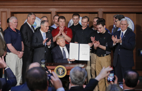 도널드 트럼프(앞줄 가운데) 미국 대통령이 지난 3월 28일(현지시간) 환경규제 철폐 행정명령에 서명한 뒤 서류를 들어보이고 있다. /워싱턴DC=EPA연합뉴스