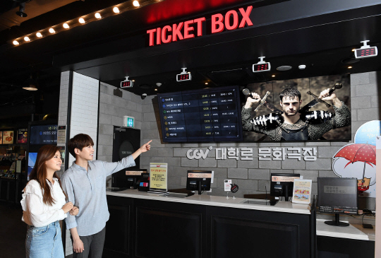 서울 대학로 CGV를 찾은 고객이 티켓 박스 내에 설치된 삼성 스마트 사이니지를 가리키고 있다./사진제공=삼성전자