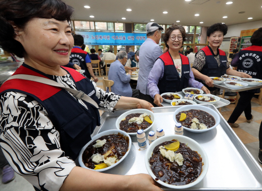 13일 서울 송파구 송파노인종합복지관에서 열린 ‘찾아가는 자장면 나눔행사’에 참여한 자원봉사자들이 복지관 이용자 및 지역 어르신들에게 자장면을 배식하고 있다. /연합뉴스