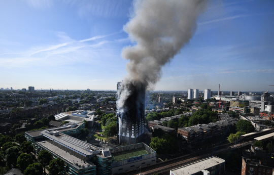 영국 런던 켄싱턴구의 그렌펠타워가 지난 14일(현지시간) 화재로 불타고 있다. 런던 켄싱턴은 고급주택이 모여 있는 지역으로 공공임대주택인 그렌펠타워에서 일어난 참사가 영국의 사회 양극화를 보여준다는 지적이 제기되고 있다.    /런던=EPA연합뉴스