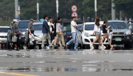 서울에 올 들어 처음으로 폭염주의보가 발령된 16일 아지랑이가 피어오르는 서울 여의대로를 시민들이 걷고 있다. 서울의 기온은 이날 32.7도까지 올랐다. 기상청은 다음주에도 전국에 걸쳐 최고온도가 34도에 오르는 등 무더위가 이어질 것으로 내다봤다. /이호재기자
