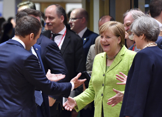 22일(현지시간) 벨기에 브뤼셀에서 개막한 유럽연합(EU) 정상회의에서 앙겔라 메르켈 독일 총리(오른쪽 두 번째)가 이날 정상회의에 첫 데뷔한 에마뉘엘 마크롱 프랑스 대통령(왼쪽)에게 미소를 건네고 있다. /브뤼셀=AP연합뉴스